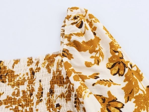 Détail du décolleté carré smocké et de l'imprimé bohème sur une robe beige clair