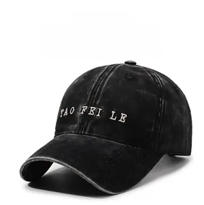 Detail of embroidered white letters on a black washed cotton vintage baseball cap