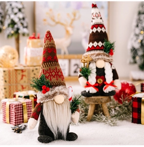 Detail of Christmas gnomes with knitted hats holding pine branches and berries in snow