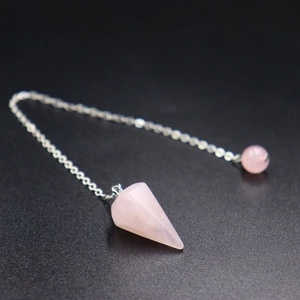 Makroaufnahme eines Pendels aus rosa Naturquarz in Hexagonalform mit Silberkette
