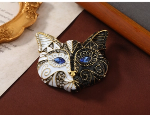 Detailed view of cat brooch with black and white enamel and blue gemstone eyes