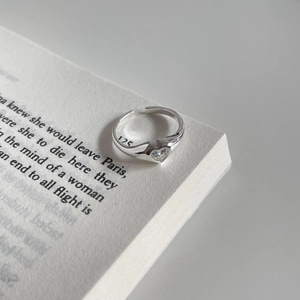 Minimalist 925 sterling silver open ring with heart-shaped zircon on a book background