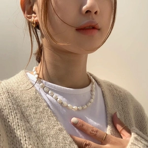 Close-up of baroque pearl necklace and minimalist gold earrings on a model