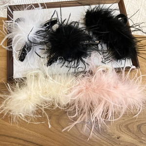 Flat lay of four elegant acrylic feather hair claws with rhinestones on a wooden tray
