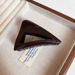 Detail showing high-gloss triangle shark hair claw clip in rich chocolate brown finish