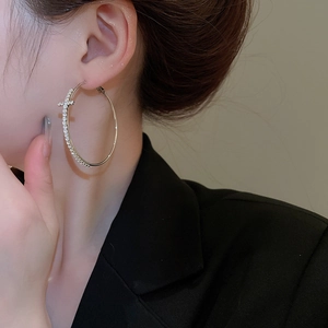 Gros plan d'un mannequin portant une créole argentée avec un pendentif croix en strass
