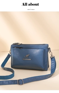 Detalle de bolso bandolera de cuero azul con varios bolsillos y logo de canguro metálico
