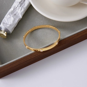 Detail of 18k gold plated stainless steel bangle with inlaid white zircons on velvet