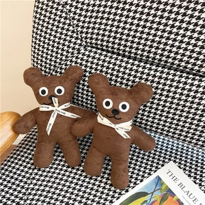 Close-up of two brown plush bears with Mini Bear ribbons on a houndstooth chair