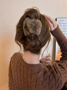 Gros plan d'une pince à cheveux en peluche marron sur un chignon de femme