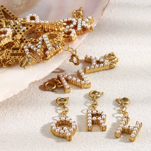 Detailed view of 18K gold plated alphabet charms with white pearls and round clasp