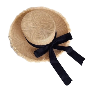 Women's beige straw flat top hat with black bow ribbon and stylish frayed edge brim