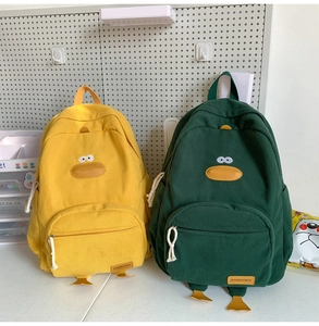 Detail view of yellow and green corduroy duck-shaped backpacks with 3D bills and feet