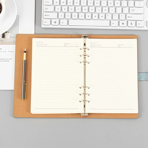 A5 light blue leather loose-leaf notebook on desk with keyboard and business pen