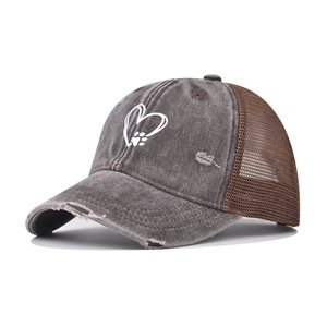 Detailed macro of a distressed denim trucker hat with heart and paw print embroidery