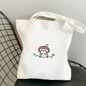Close-up of a white canvas tote bag featuring a cute frog wearing a mushroom hat print