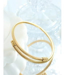 Macro detail of a twisted gold titanium steel bangle with elegant open cuff design