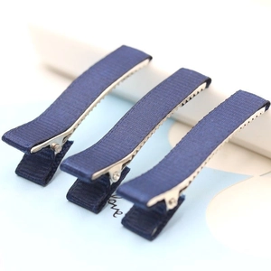 Detailed close-up of three navy blue grosgrain ribbon wrapped duckbill hair clips with teeth