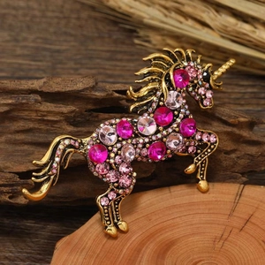Vintage unicorn brooch with pink crystals and bronze base over a natural background