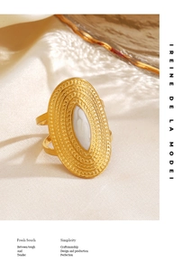 Macro view of gold-plated oval ring featuring white shell inlay and radiant textures