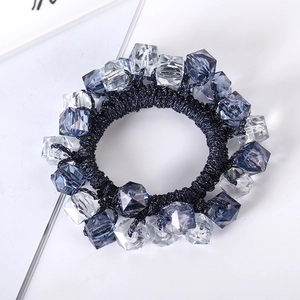 Detail of navy blue elastic hair tie with faceted crystal beads on white surface