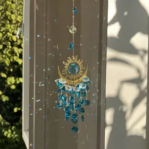 Golden sun and moon crystal suncatcher with blue crystals reflecting rainbow light in a garden