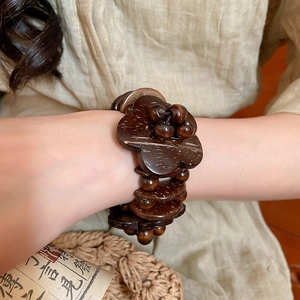 Close-up of a deep brown coconut shell flower beaded bracelet on a model's wrist