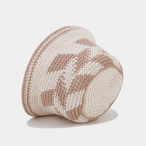 Detail of hand-knitted hollow diamond pattern on beige and white crochet bucket hat