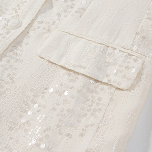 Vista dettagliata del tessuto jacquard con paillettes bianco crema e bottone abbinato