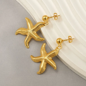 Exaggerated golden starfish drop earrings with textured metal finish on a display
