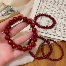 Detailed view of deep red cinnabar beaded bracelets in various sizes on ancient calligraphy