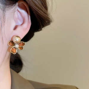 Detail of 18k gold pearl stud earring with brown enamel flower and zircon on model