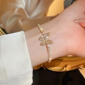Elegant gold butterfly bracelet with white zircon stones on a luxury satin background