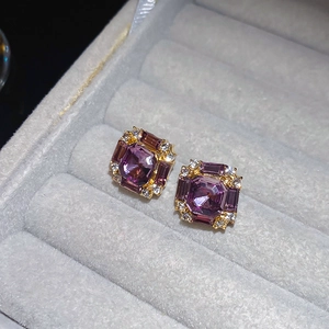 Macro shot of square purple gemstone stud earrings with crystal halo in a velvet box