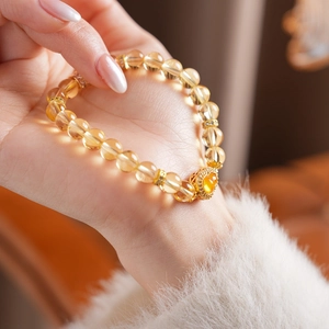 Gros plan d'un bracelet en perles de citrine jaune avec breloque cœur au poignet