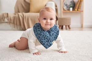 Close-up of a baby wearing a blue leopard print cotton bib with waterproof layer