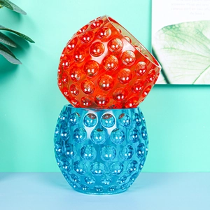 Detail view of round textured glass candle jars with red and blue dotted relief patterns