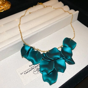 Detail of gold chain necklace featuring matte dark green petal pendants on fabric display