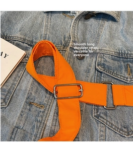 Detail of adjustable bright orange nylon strap with silver metal buckle on denim jacket