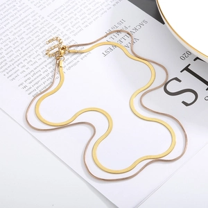 Double-layered snake bone chain necklaces in gold and rose gold on stylish paper background