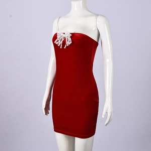 Detail of red tube dress with white lace bow and pearl pendant on velvet fabric