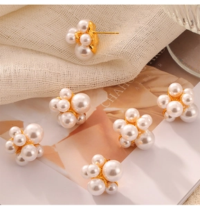 Close-up of cluster pearl stud earrings with gold base on minimalist linen background