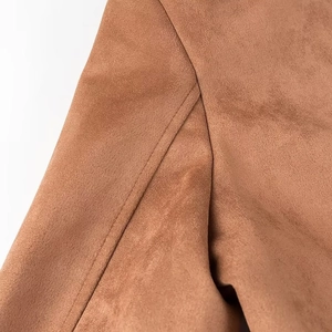Detailed close-up of double-stitched seams on tan suede coat fabric texture