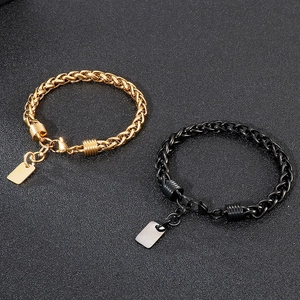 Black and gold wheat link stainless steel bracelets with blank tags on dark background