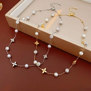 Detailed close-up of gold and silver necklaces featuring pearls and clover flower pendants