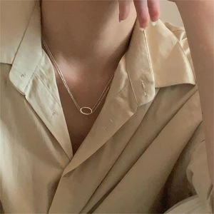 Minimalist double-layered silver necklace with oval pendants worn on a female model