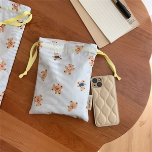 Blue striped cotton drawstring bag with bear print and wavy texture phone case on wood table