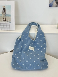 Blaue Denim-Tragetasche mit weißem Sterndruck und Markenlabel auf weißer Fläche