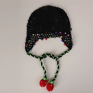 Detail of crochet beanie featuring colorful beads and handcrafted strawberry tassels