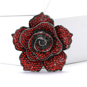 Vintage rose flower brooch with red rhinestones and dark metal finish on white background